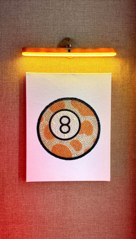 Rhinestone-bedazzled canvas wall art of an orange cow print 8-ball.