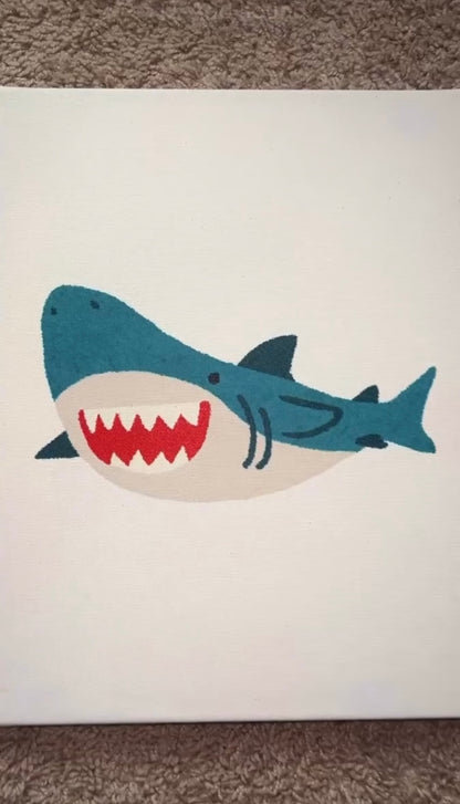 Hand-bedazzled canvas wall art depicting a blue shark with a open mouth, created using rhinestones.