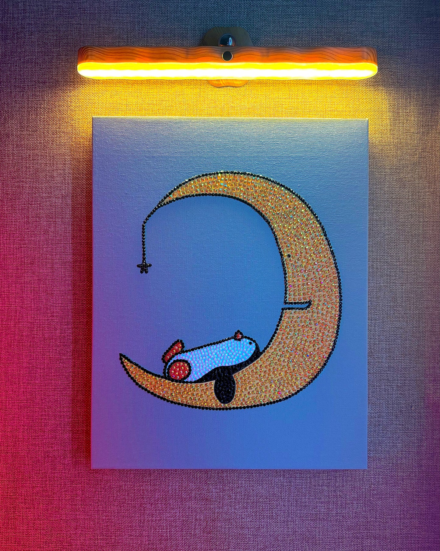 Illustration of a rhinestone-bedazzled canvas art penguin sleeping on a crescent moon with a warm light above.