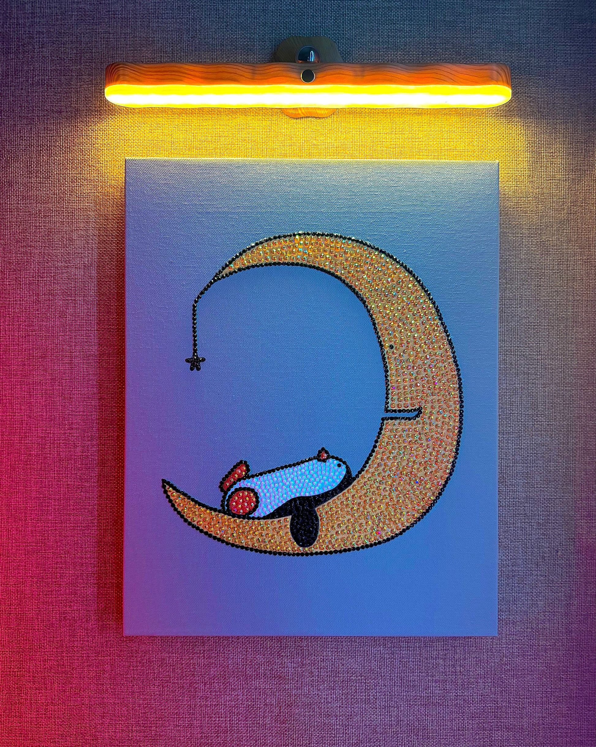 Illustration of a rhinestone-bedazzled canvas art penguin sleeping on a crescent moon with a warm light above.