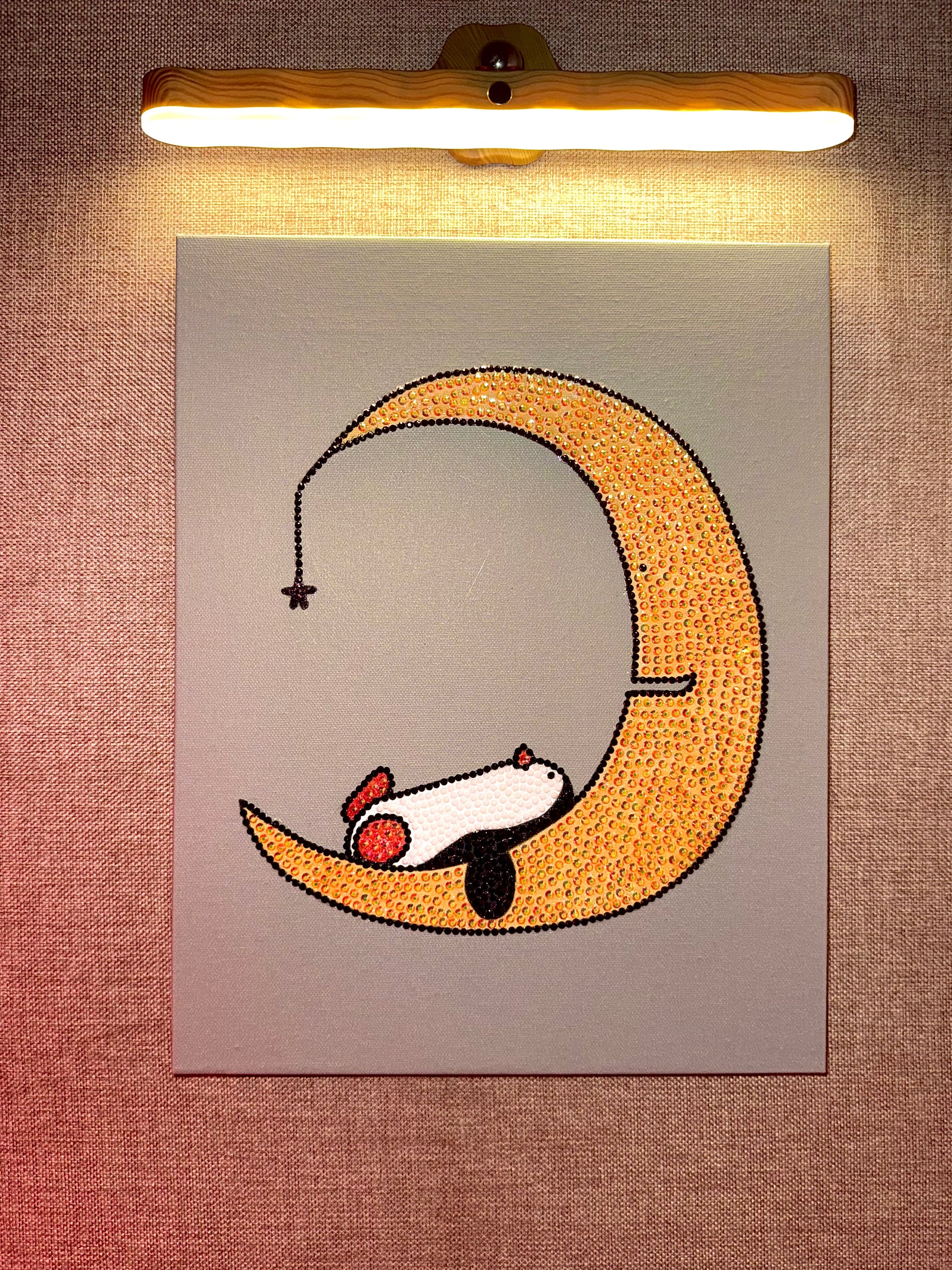 Rhinestone-bedazzled canvas art of an illustrated penguin sleeping on a crescent moon with a warm light above.